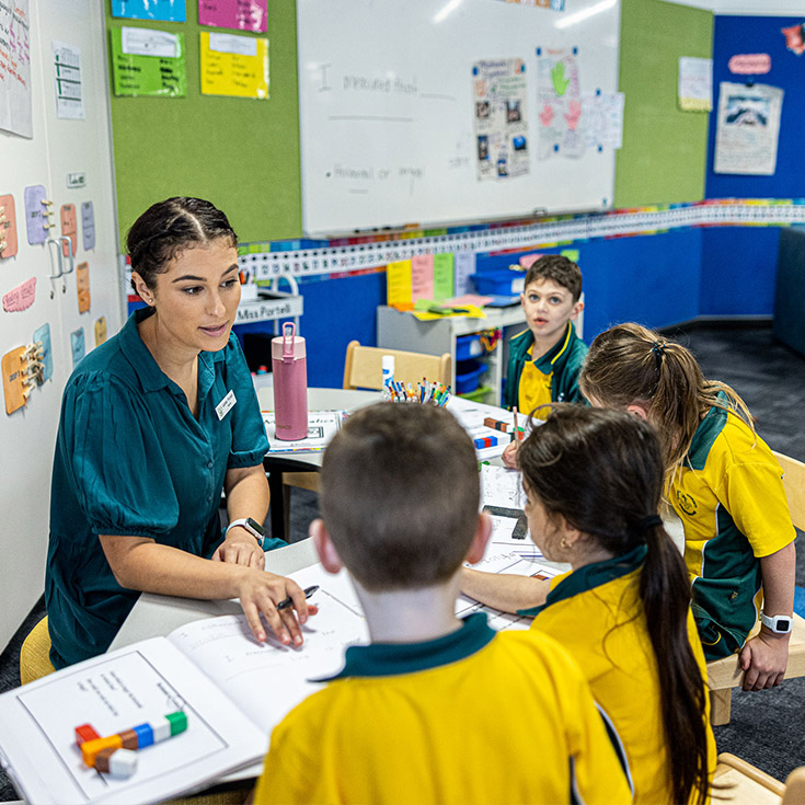 Teacher helping students at Corpus Christi Catholic Primary School Cranebrook