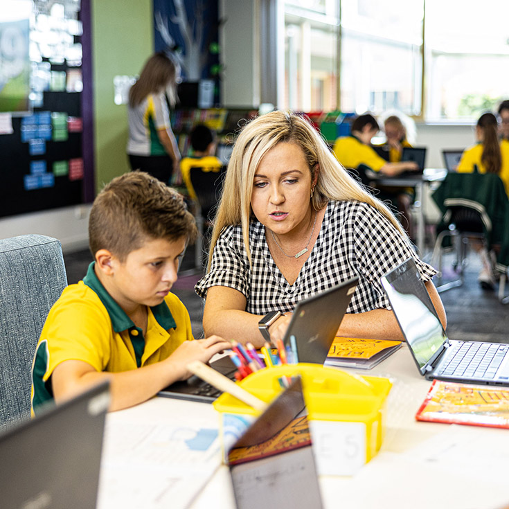 Teacher helping student at Corpus Christi Catholic Primary School Cranebrook
